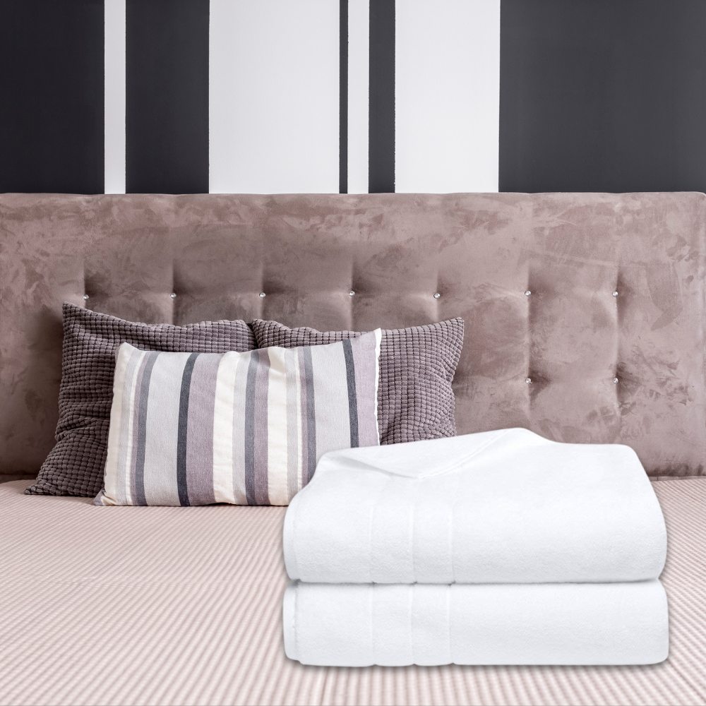 Two folded white bath sheets on a made bed